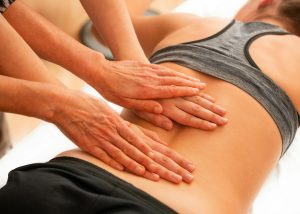 A woman receiving a therapeutic back massage from a professional physical therapist in a serene setting