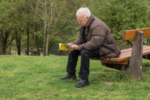 a old man is siting in the garden with the book