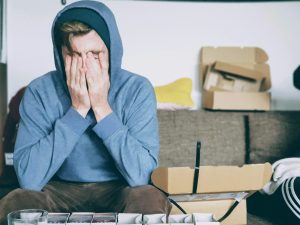 A man relaxes on a couch, enjoying a box of pizza placed beside him